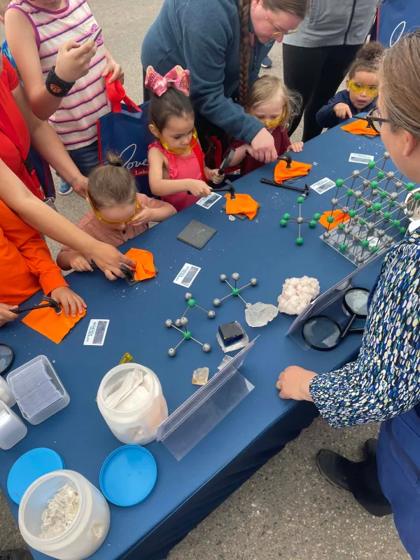 A large group of children and adults overhead photo. They are all engaging in a salt molecule activity to see how salt breaks down and looks under a magnifying glass.